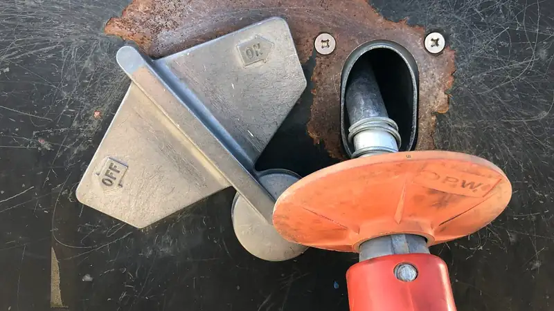 A red fuel nozzle inserted into a car's open fuel filler.