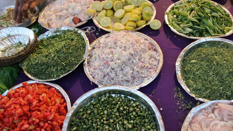 Trays of chopped tomatoes, greens, onions and limes laid out for cooking.