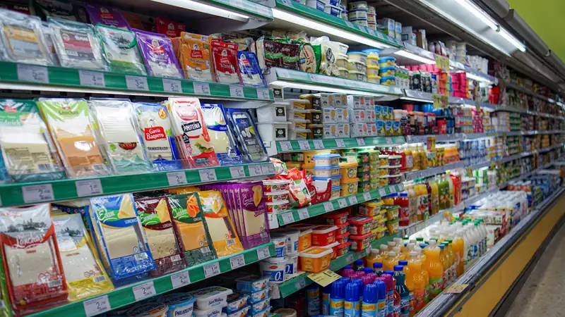 A supermarket dairy aisle stocked with packaged cheese, yogurt and juice.